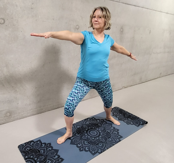 A person standing on a mat with her arms out Description automatically generated